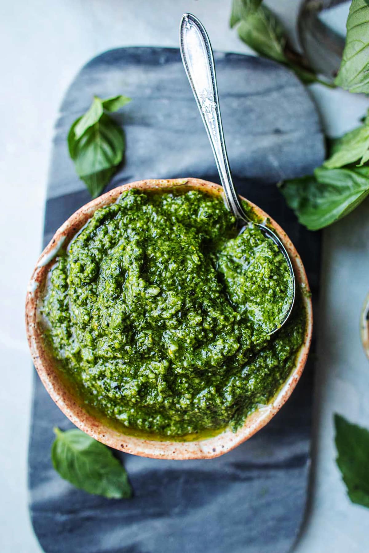 thai basil pesto sauce in a bowl with a spoon on the side