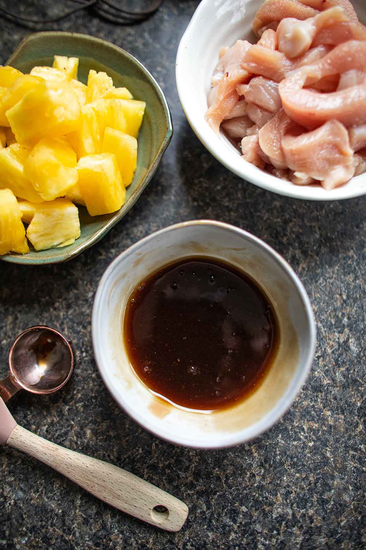 Sweet and sour sauce on a counter with chicken and pineapple.