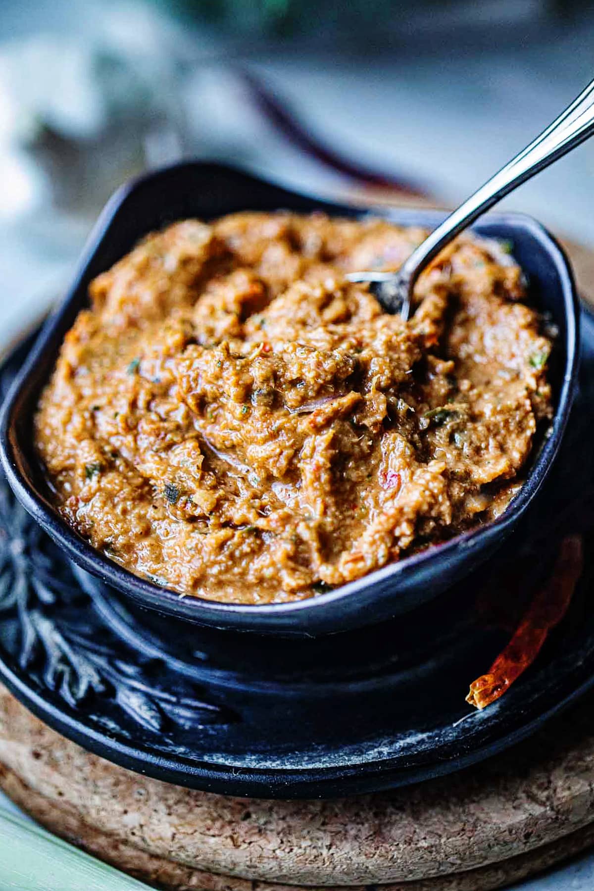 Spoon inside Tom Yum Paste in a black bowl. 