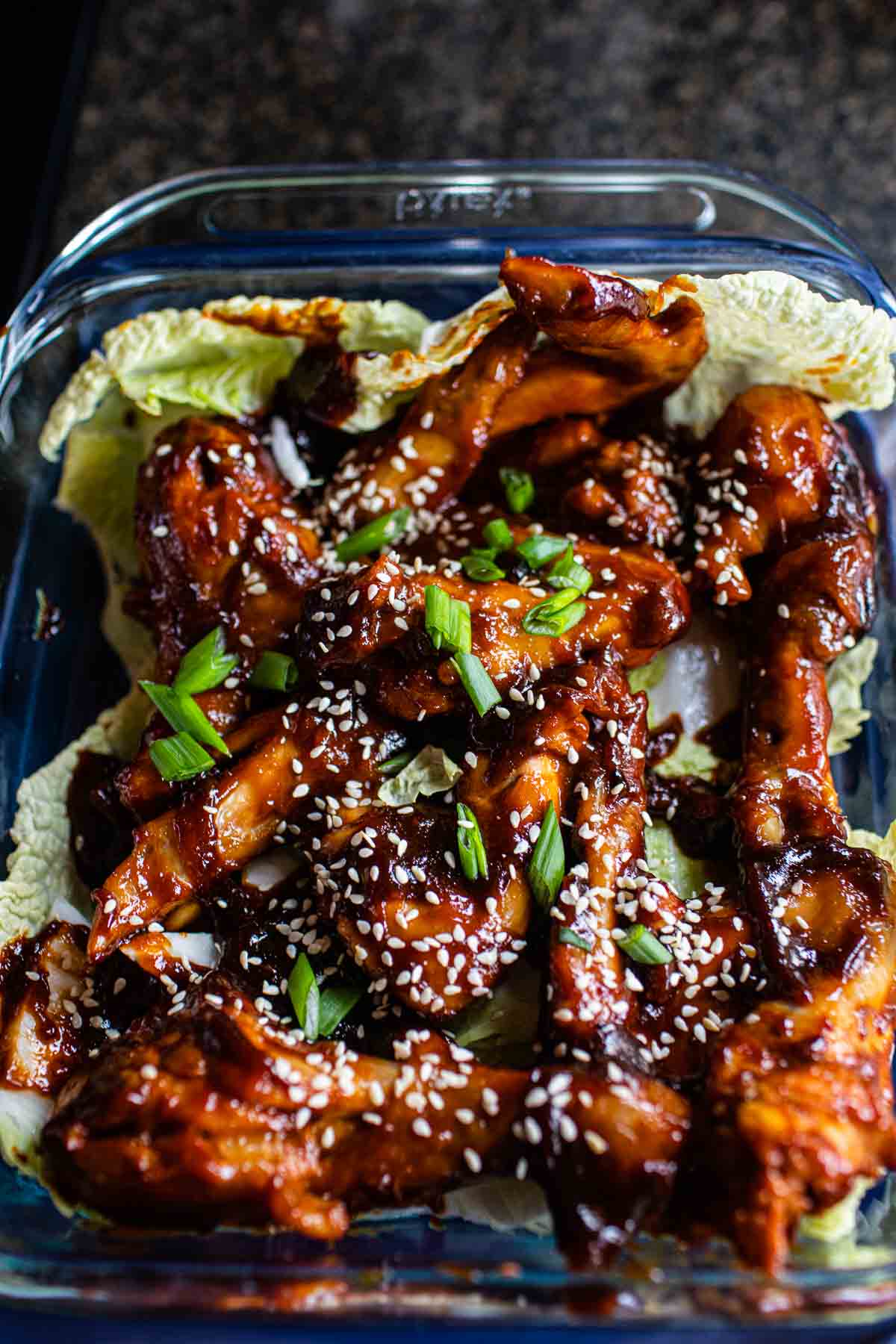 chicken wings with sriracha and hoisin over a bowl of lettuce.