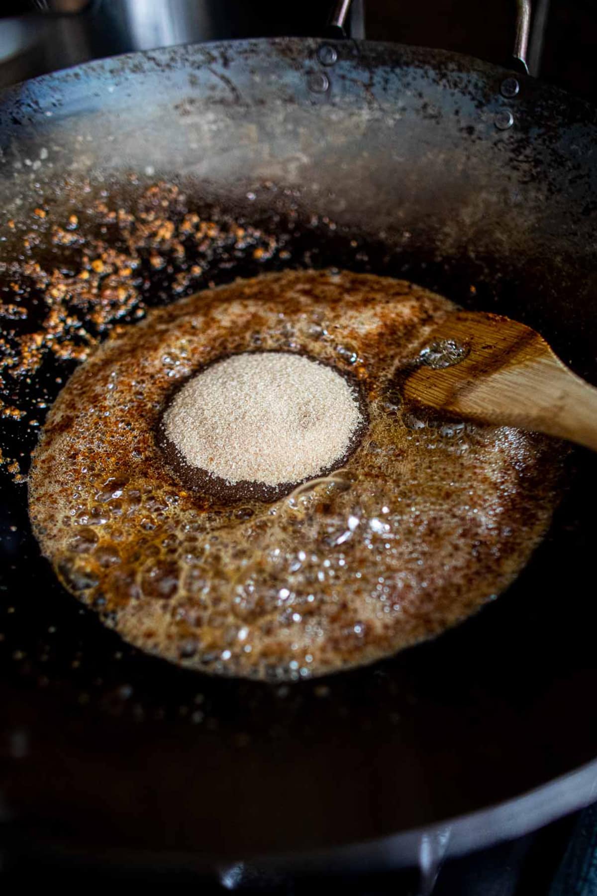 Sugar added to Nam Prik Pao Paste frying in a wok.