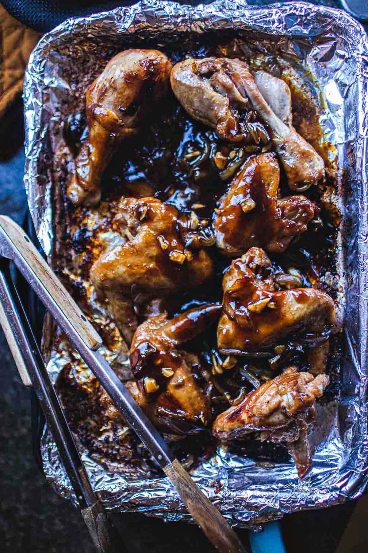cooked wings with caramelized onion sauce on a baking sheet.