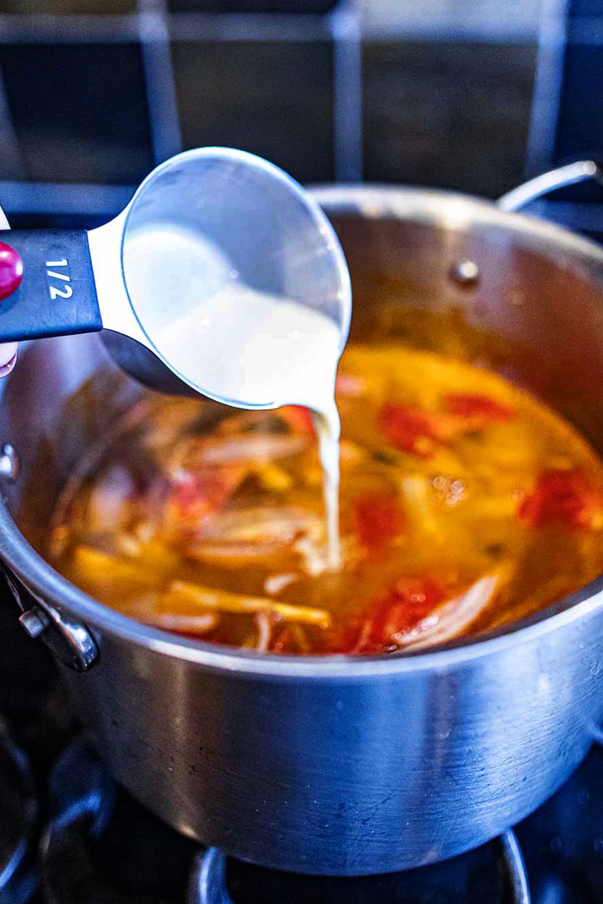 Evaporated milk added to a pot of Tom Yum broth.