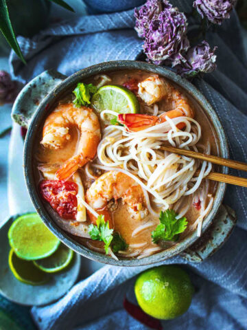 Creamy Tom Yum soup with noodles in a bowl on the table.