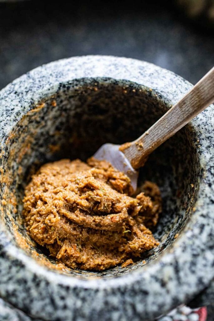 Tom yum paste in a mortar with a spatula inside.