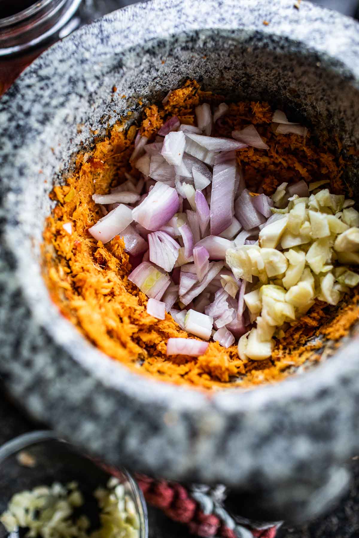 garlic and shallot in tom yum paste in a mortar.