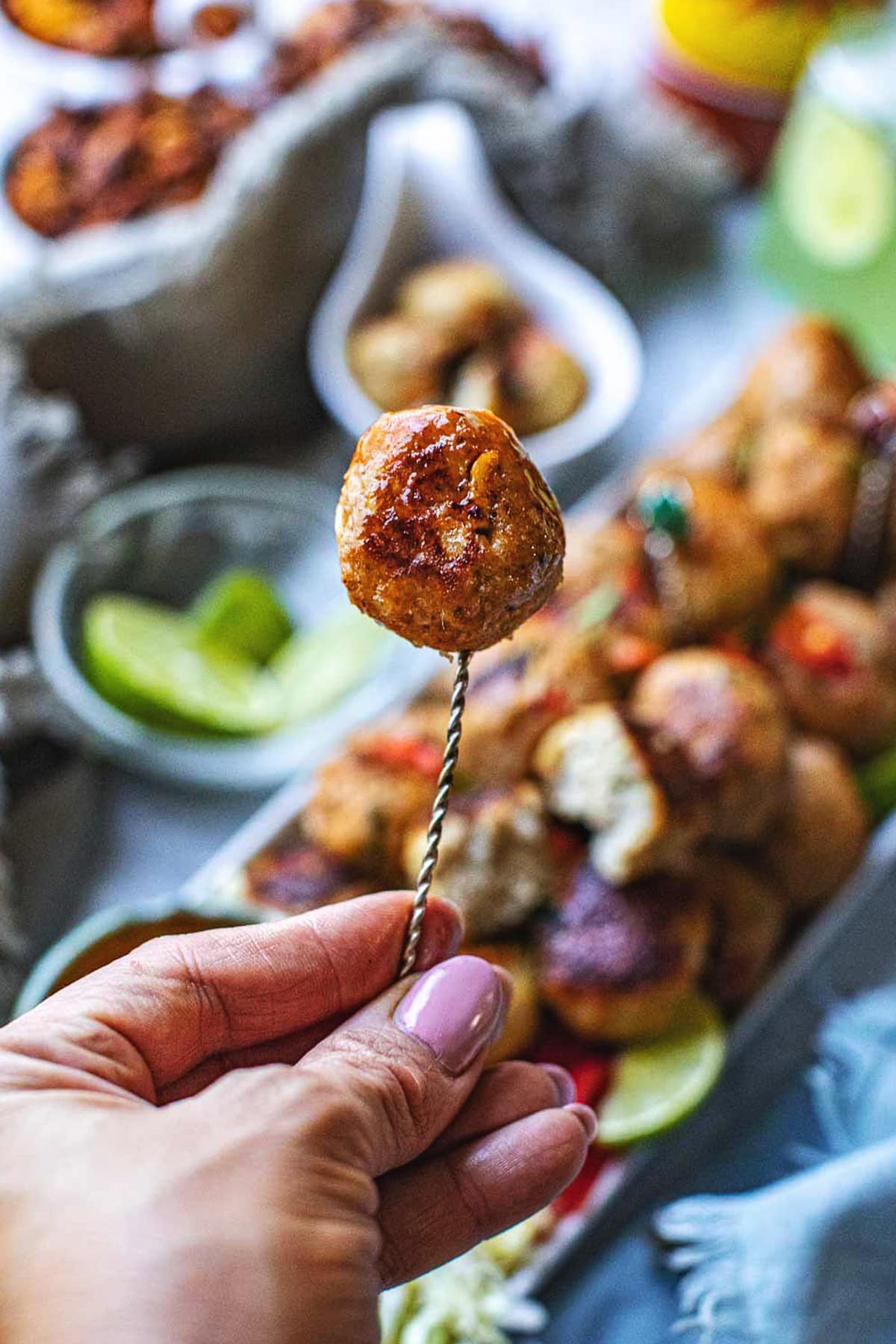 Hand holding Thai tom yum meatball on a stick.