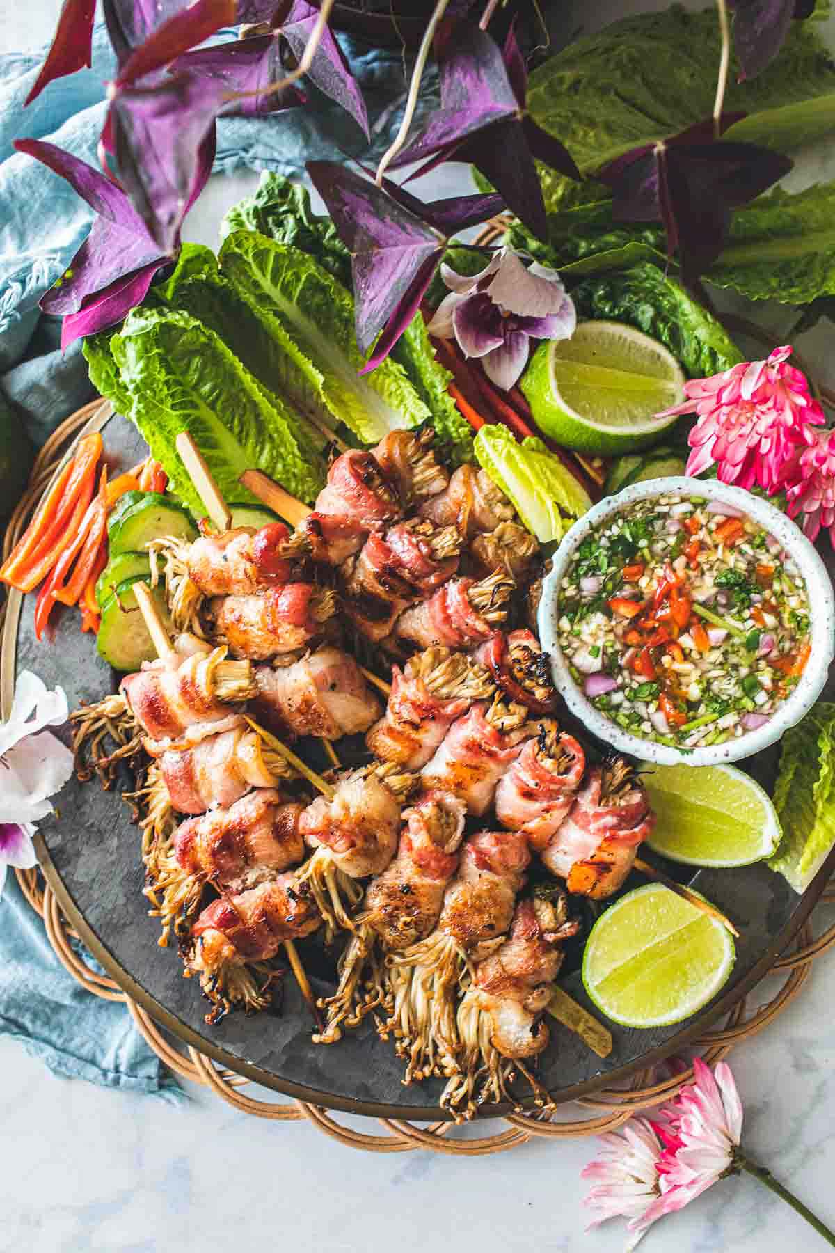 Enoki mushroom wrap with a bowl of chili sauce on a platter. 