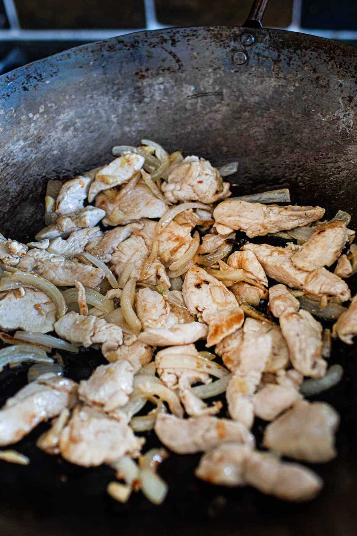 Chicken, ginger and onion stir fry in a wok.