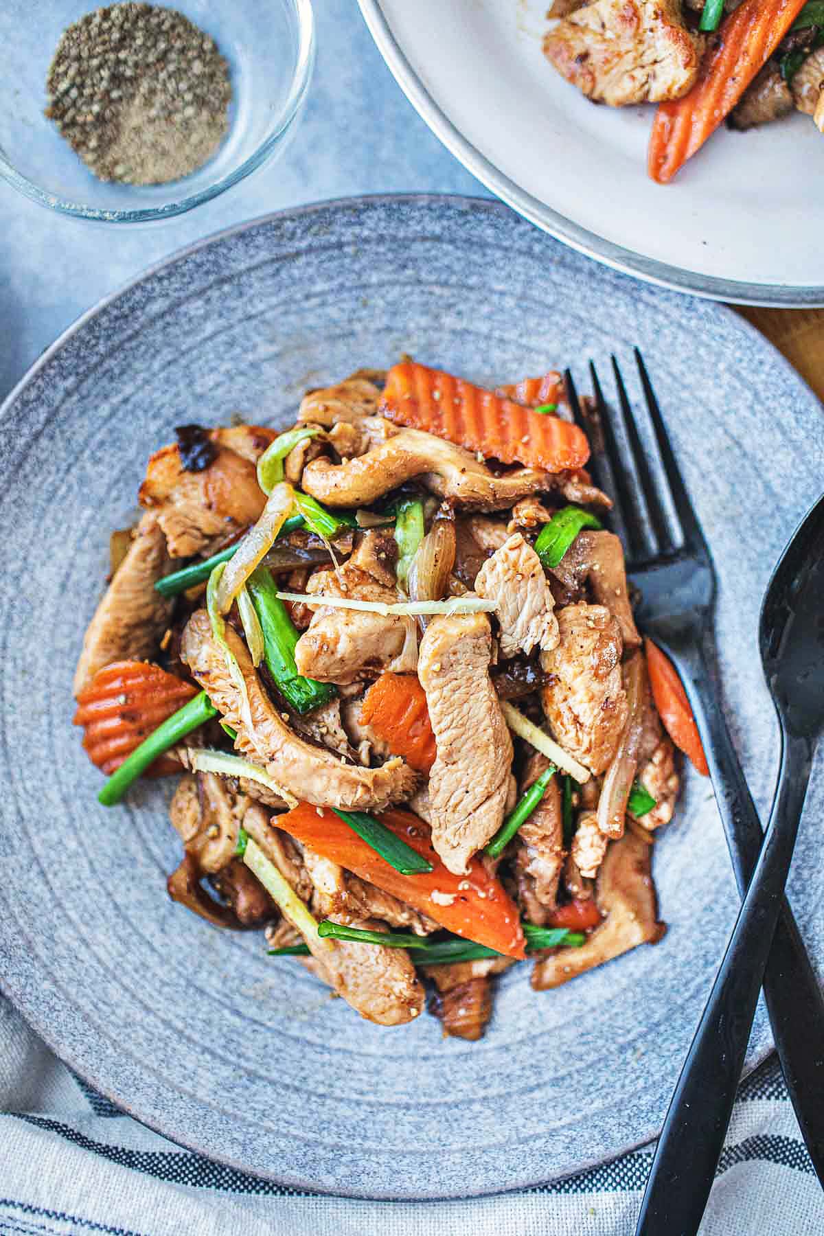 Thai ginger chicken on a plate with a fork and spoon.