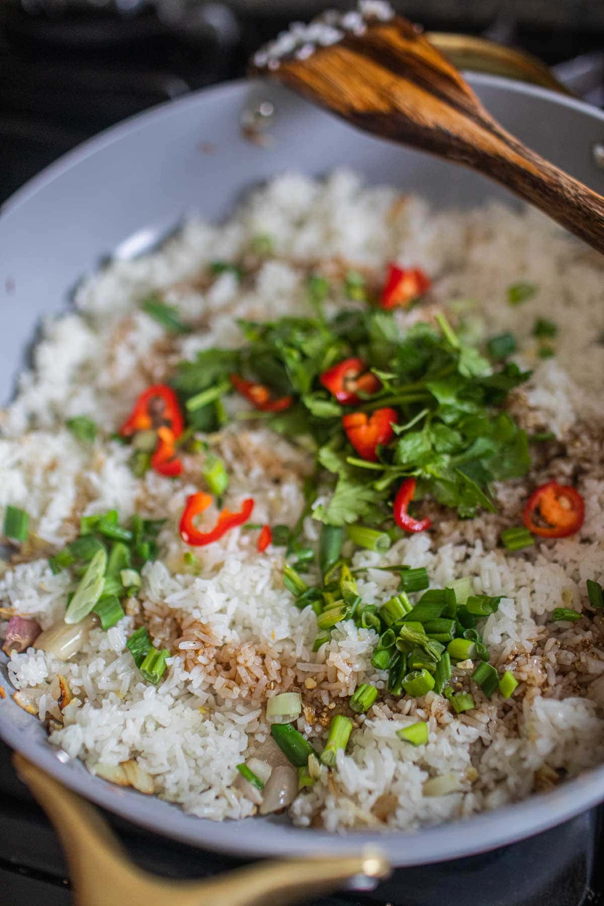 Fried rice in a pan with scallions and pepper.