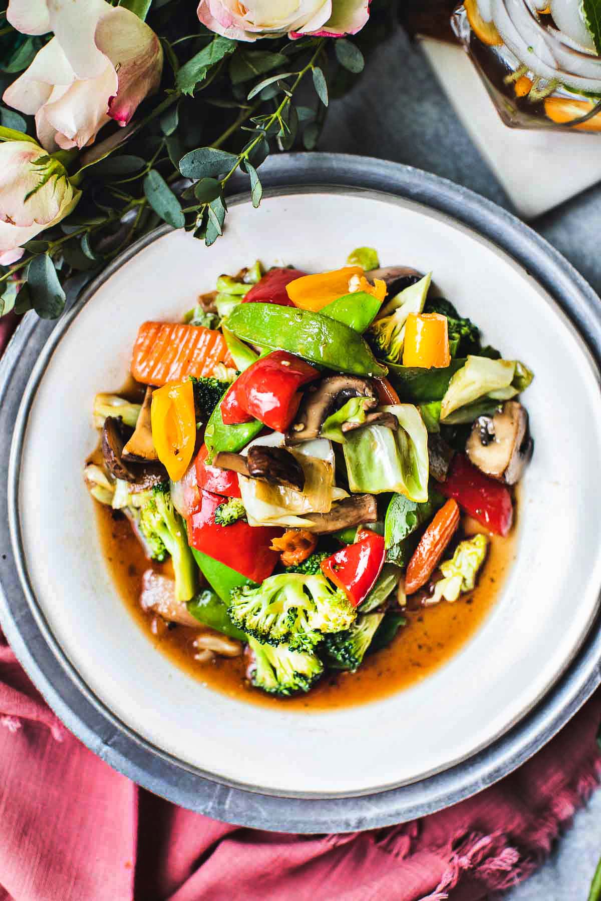 Pad Pak Roum Mit a Thai mixed vegetable stir fry on a white plate on the table.