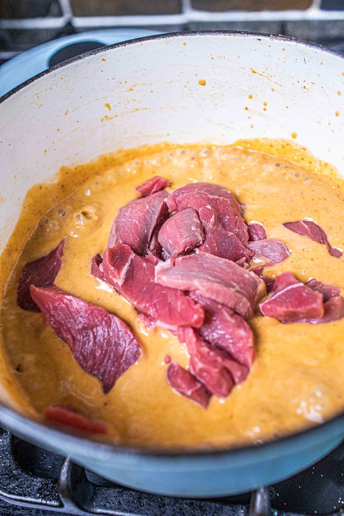 Beef slices in a Panang curry with  in a pot of curry sauce. 