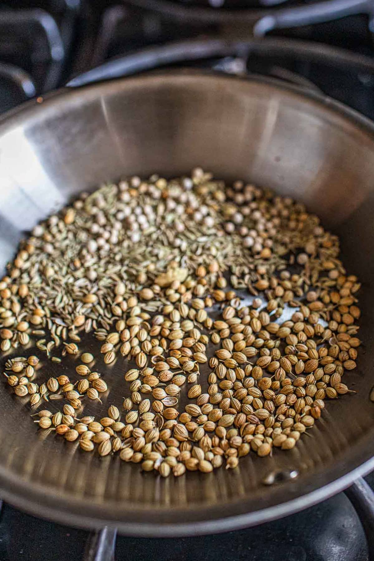 Whole spices toasted in a pan on the stove. 