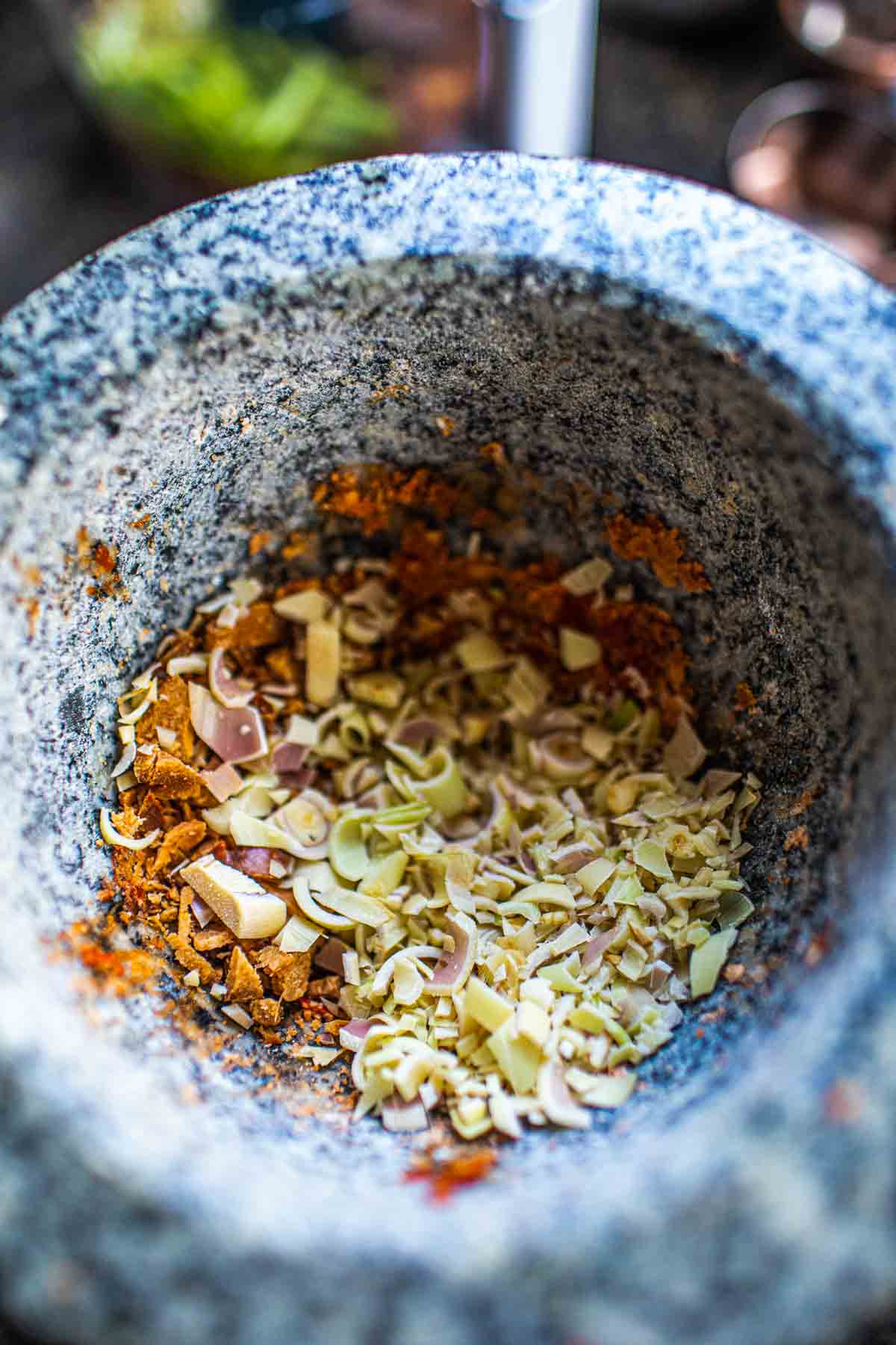 Lemongrass and galangal with curry paste in a mortar.