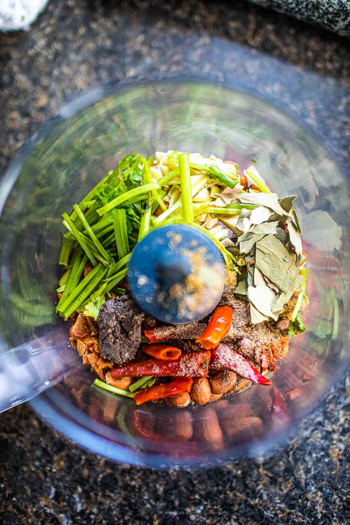 Fresh herbs and spices with curry paste in a food processor.