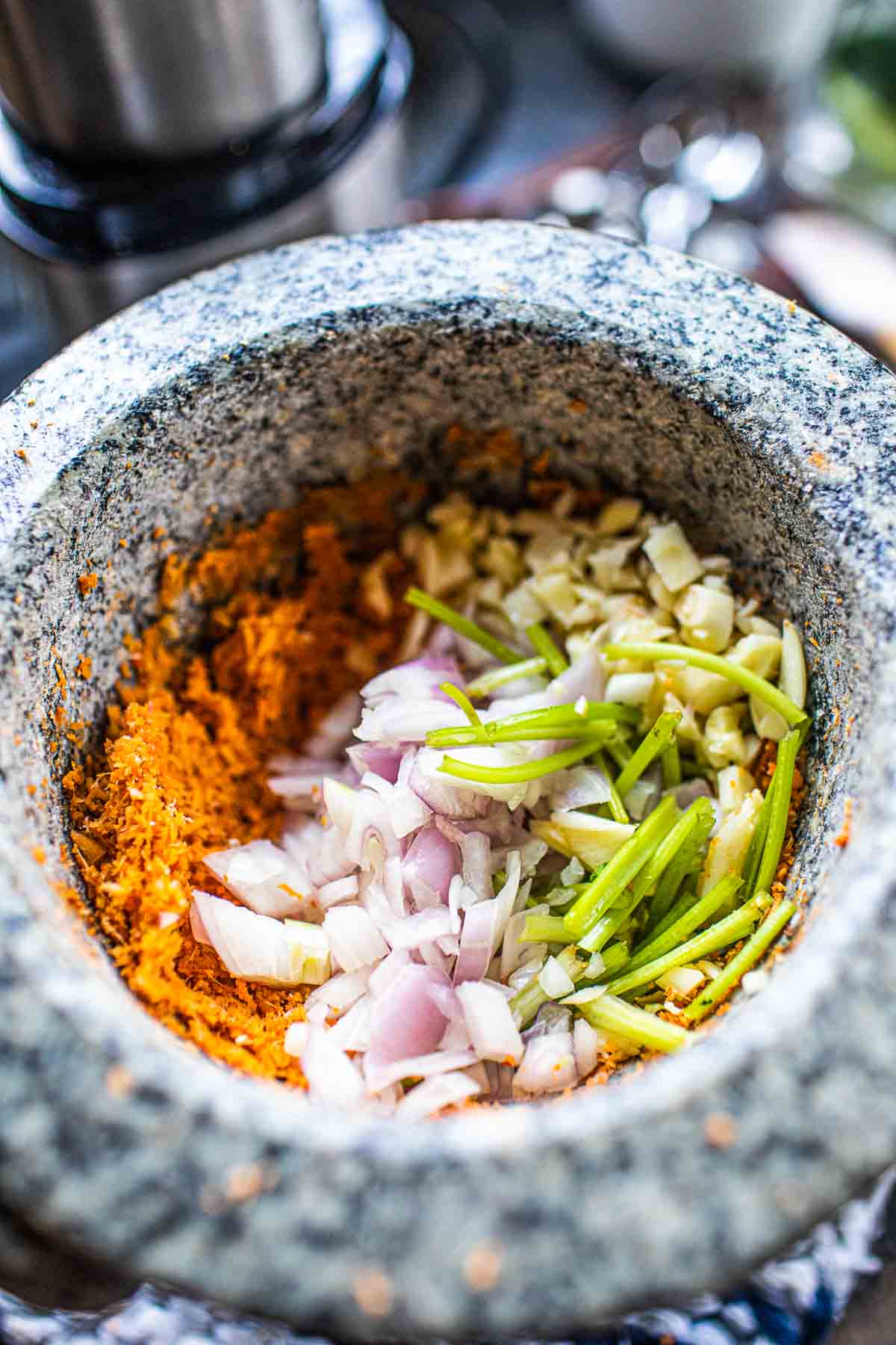 Fresh herbs with curry paste in a mortar.