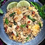 Thai basil fried rice on a plate with lime wedges.