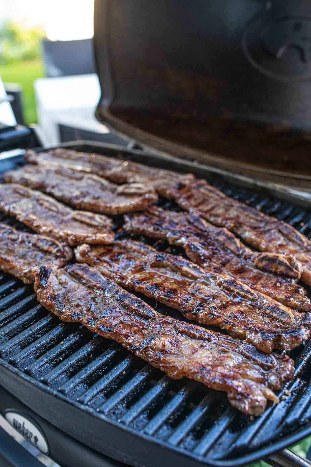 Thai beef ribs grilling on a grill.