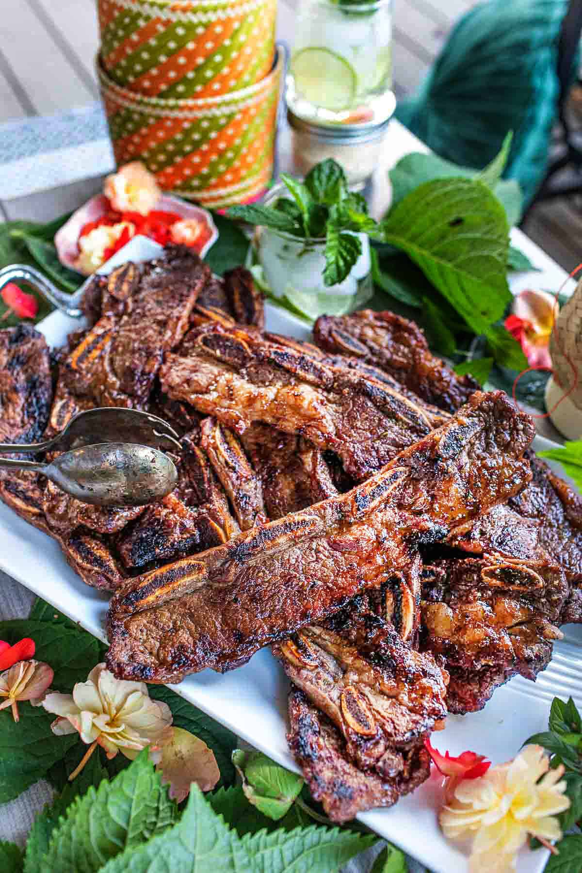 Asian beef ribs on a platter with green garnishes.