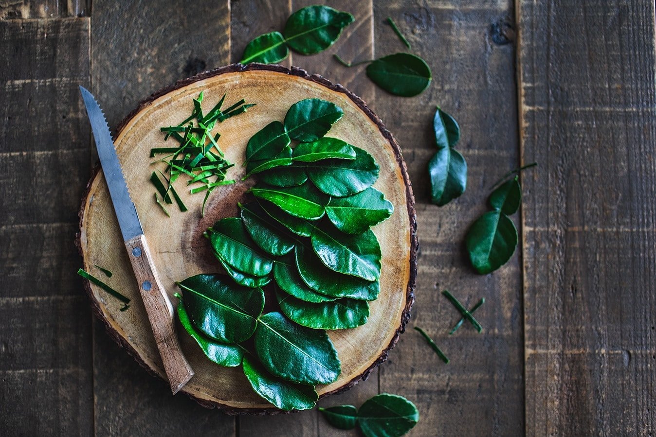 Kaffir lime leafs on a cutting board.