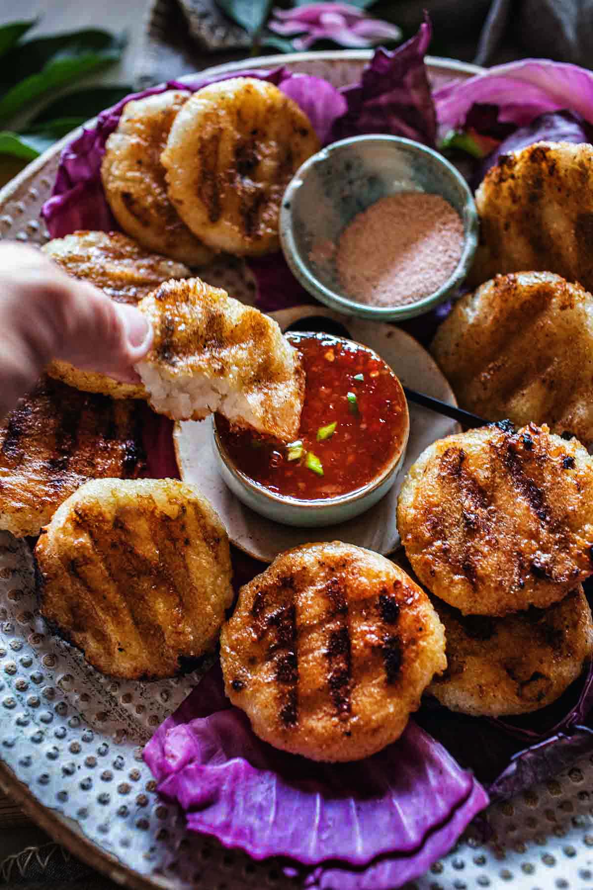 Lao grilled sticky rice patties on a tray with chili dipping sauce.