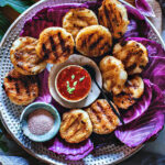 Khao Jee Sticky Rice Patties on a platter with dipping sauce.