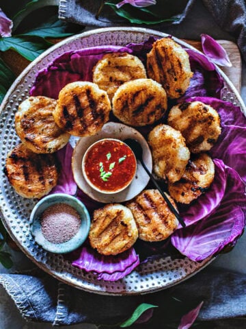 Khao Jee Sticky Rice Patties on a platter with dipping sauce.