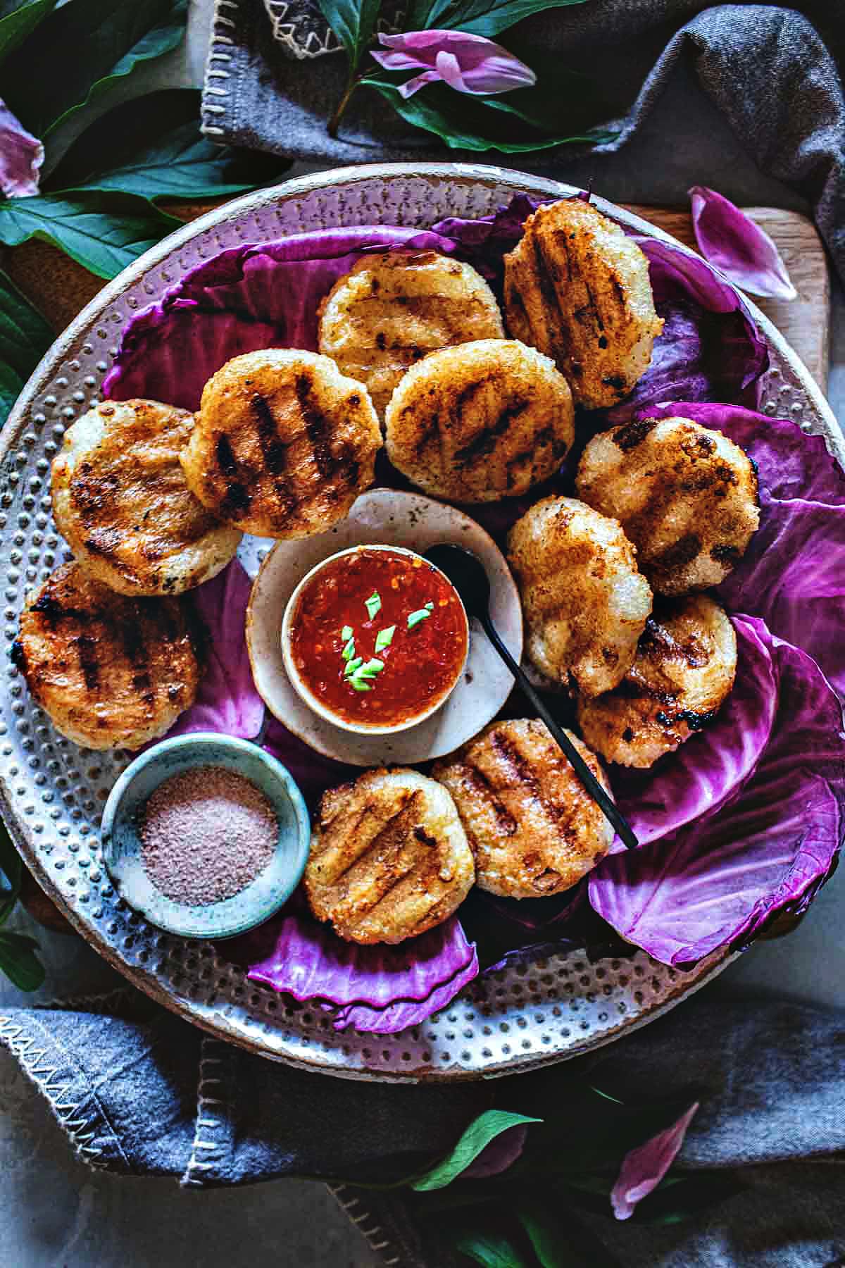 Khao Jee Sticky Rice Patties on a platter with dipping sauce.