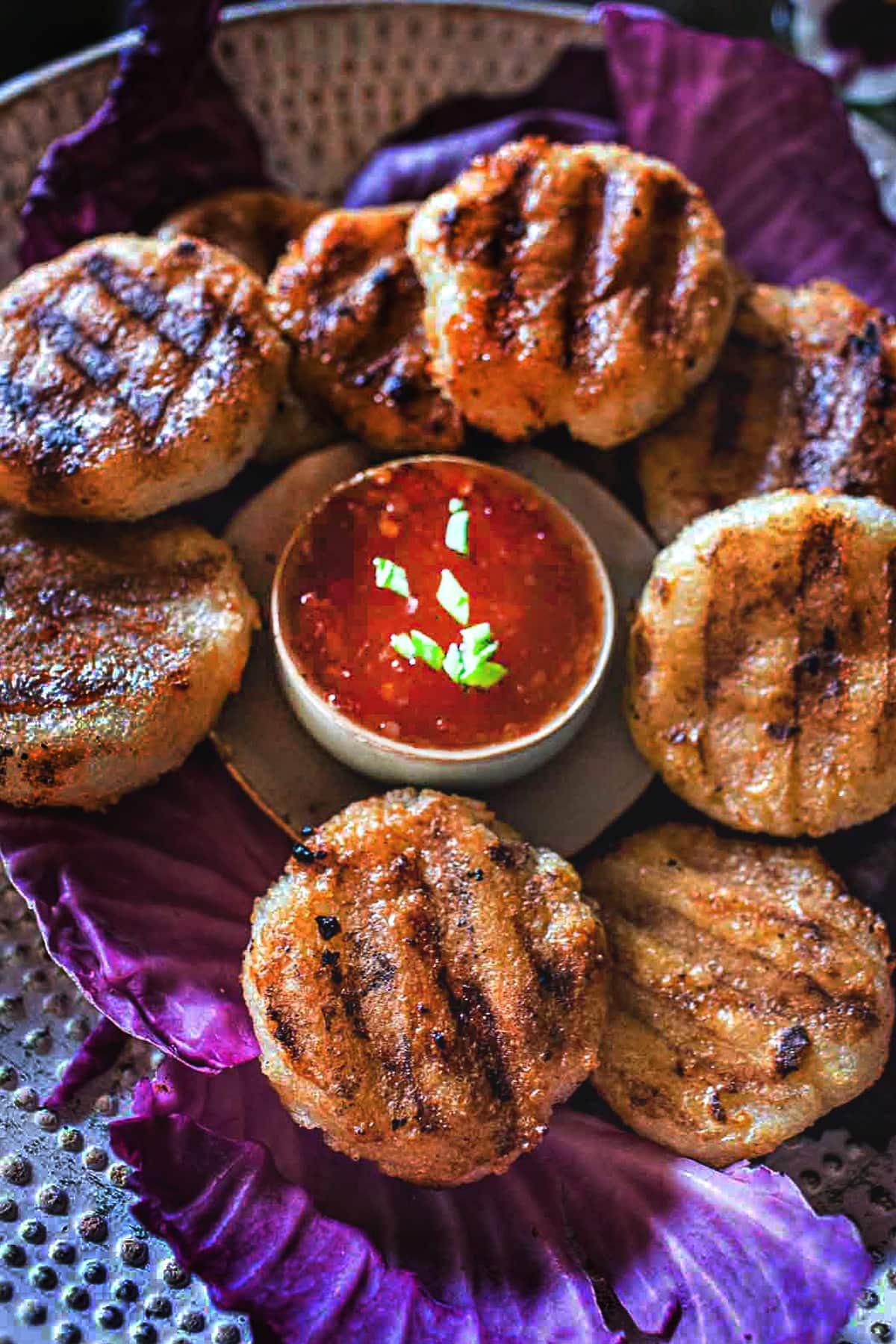 Khao Jee rice patties on a tray with dipping sauce .