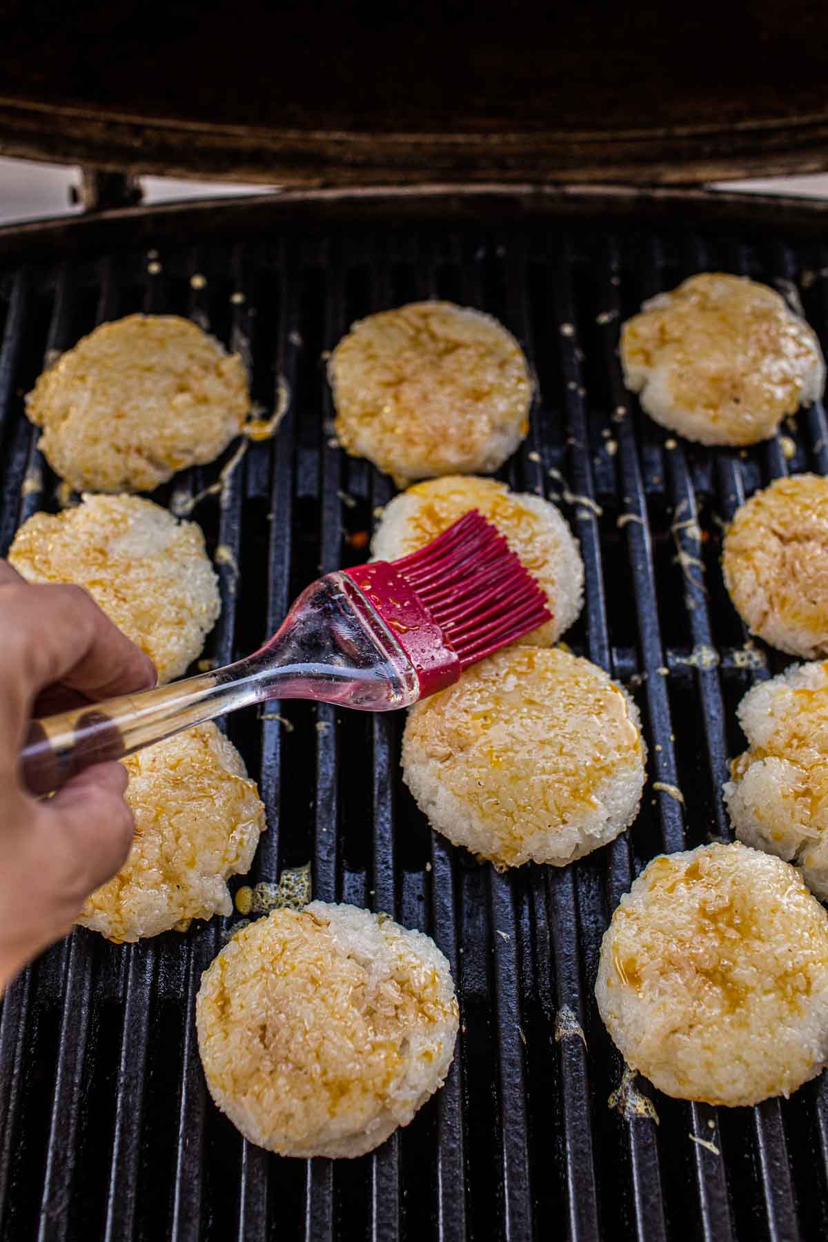 Lao Grilled sticky rice patties on the grill with a brush on patties.