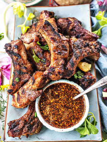 Thai Grilled BBQ pork ribs on a platter with chili sauce.