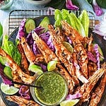 Thai grilled shrimp on a platter with green sauce.