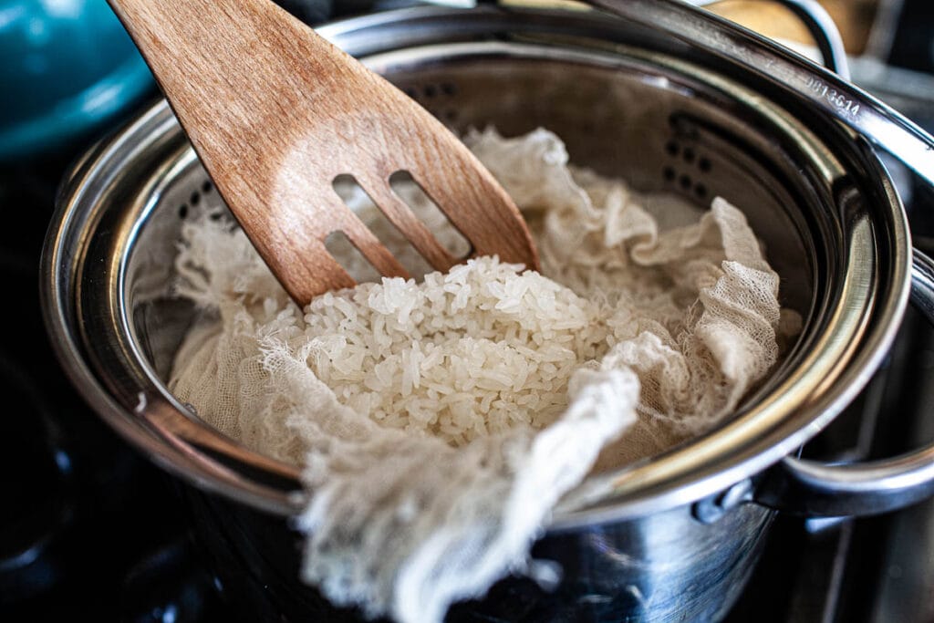 Spatula lifing Thai sticky rice from a pan.