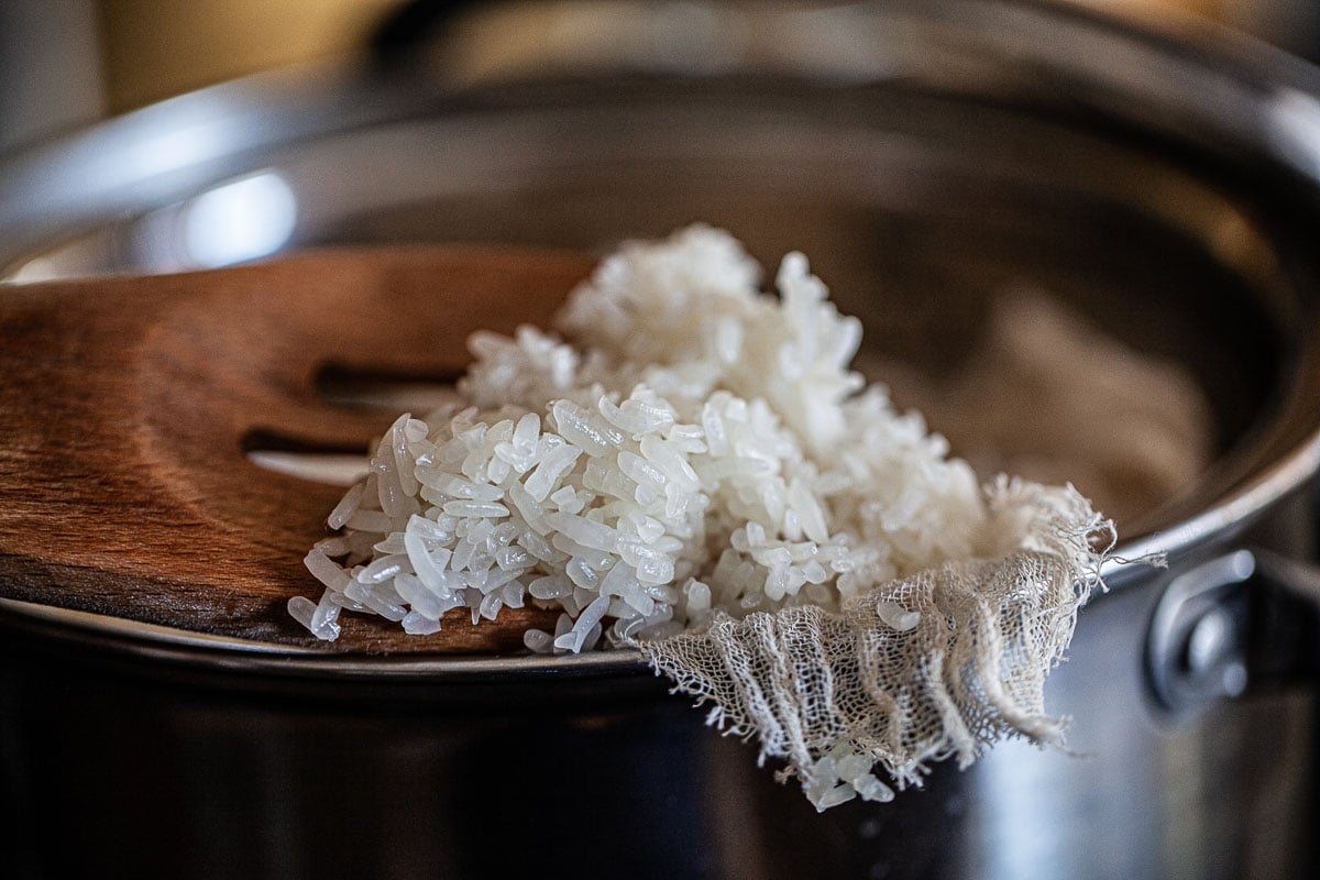 Wooden spoon lifting Sticky rice in a pot.