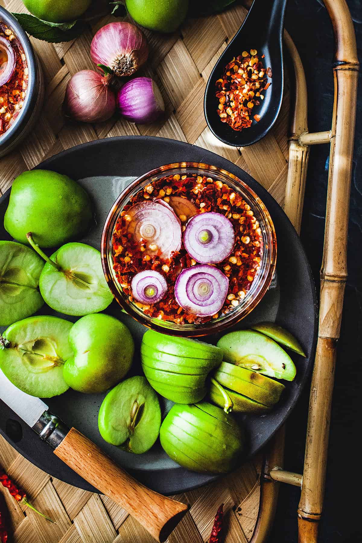 Thai spicy sweet dipping sauce on a tray with green apples. 