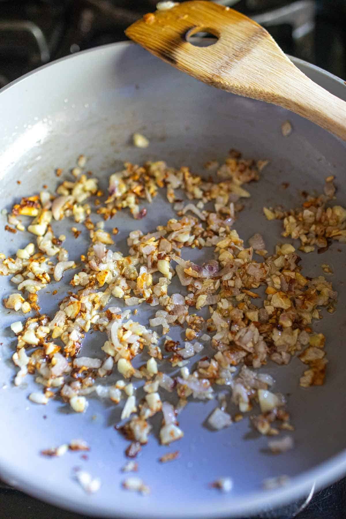 garlic and shallot frying in a pan.