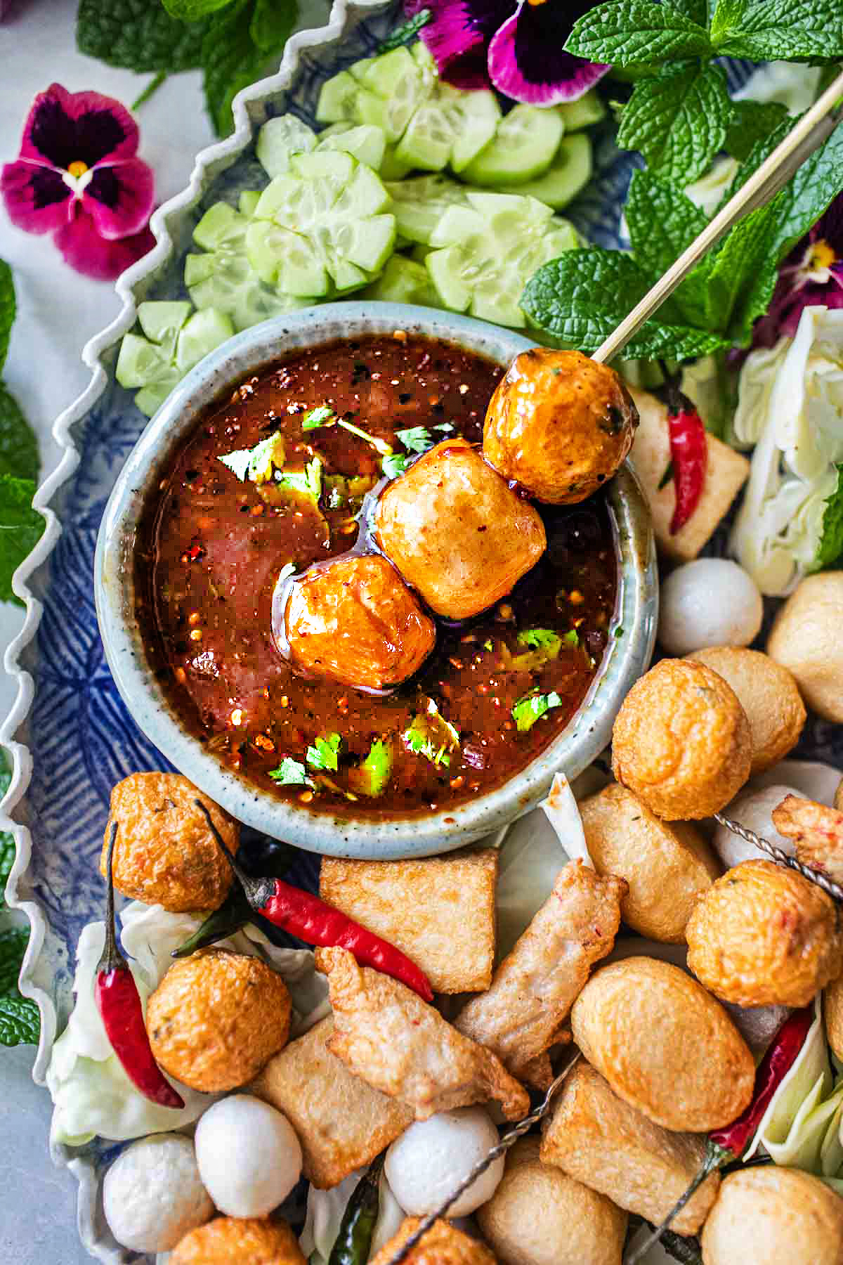 Tamarind sauce in a bowl with meatballs around on the platter.