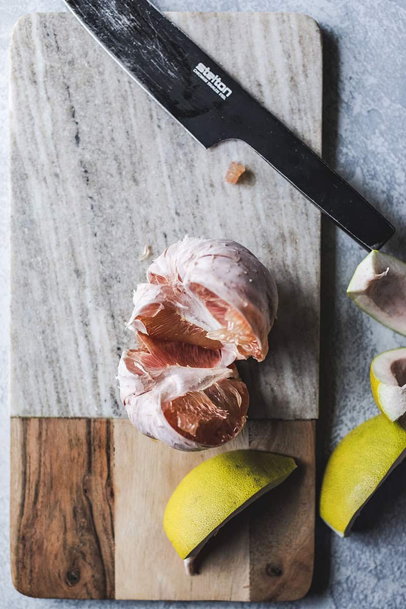 Cut Pomelo slices in a bowl on a cutting board. 