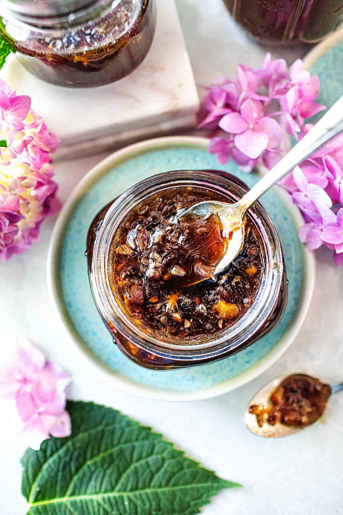 Spoon lifting pad thai sauce in a glass jar. 