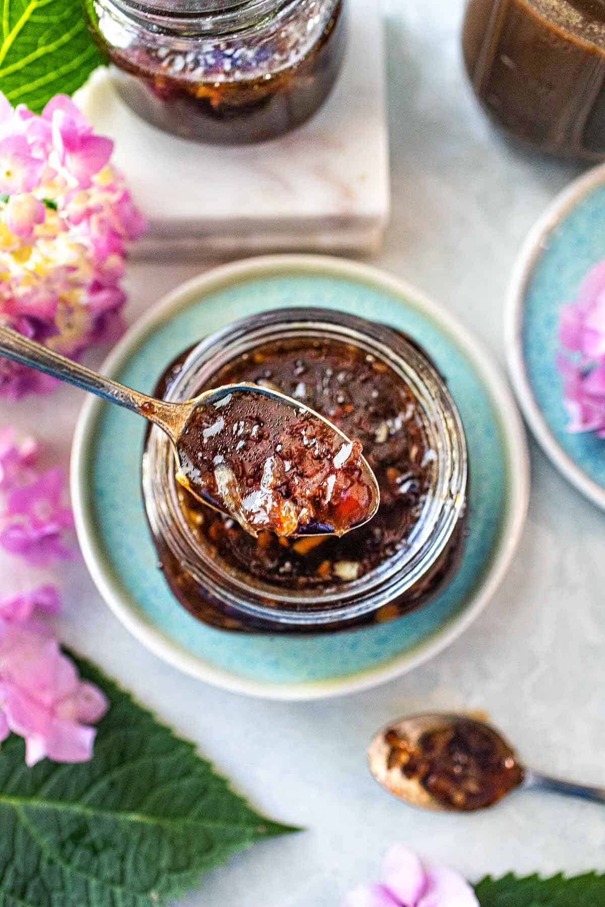 Spoon lifting pad thai sauce from a glass jar.