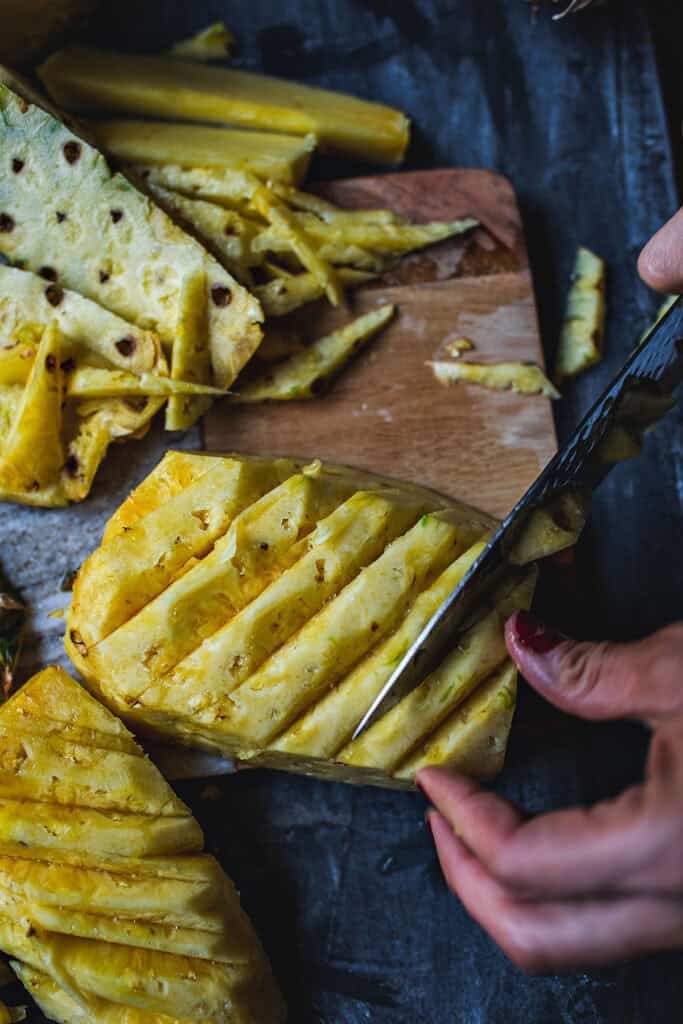 Cutting eyelets of pineapple on a board