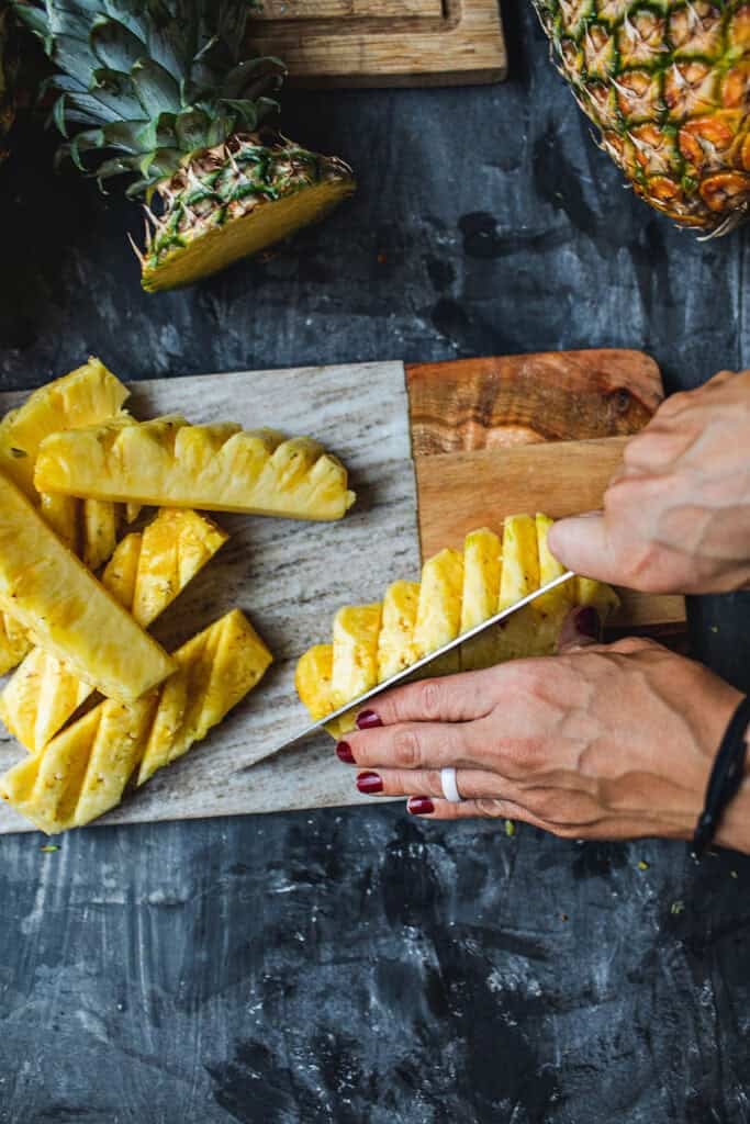 Cutting pineapple into small bites.