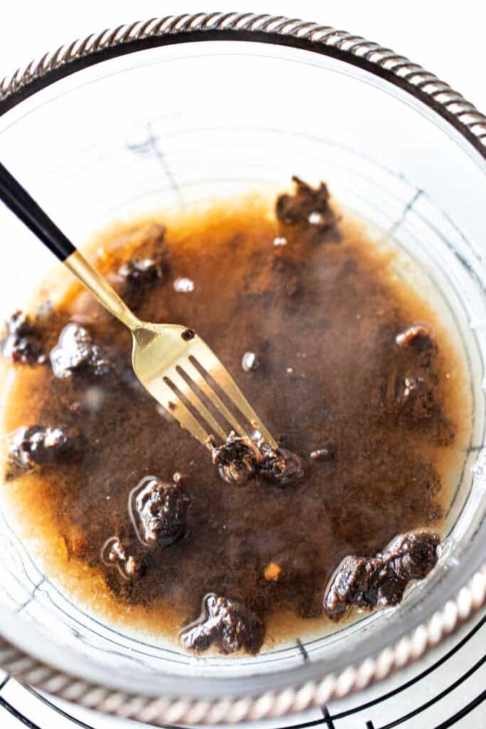 A fork meshing Tamarind paste in a glass bowl.