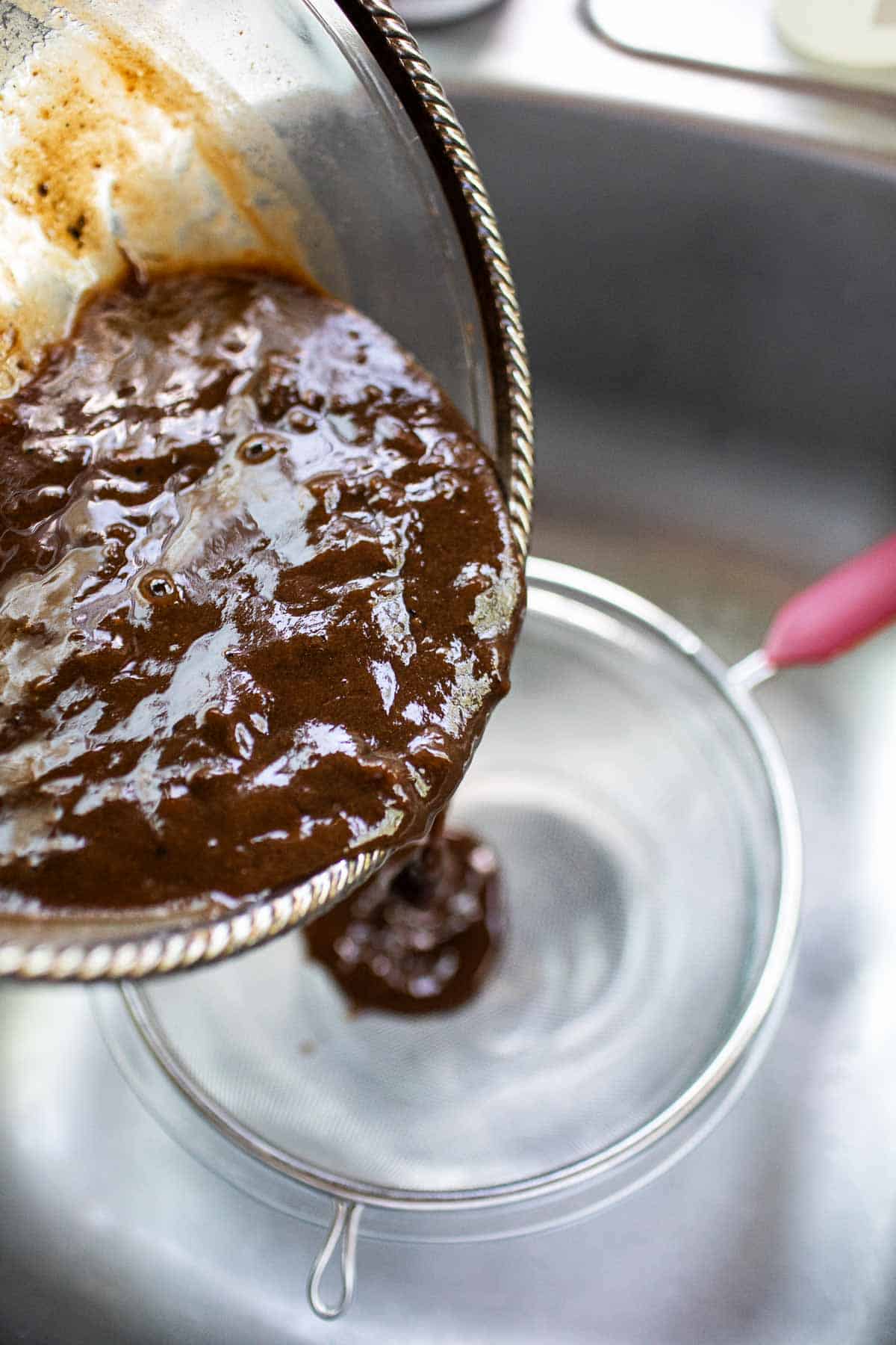 Pouring  tamarind paste into a strainer.