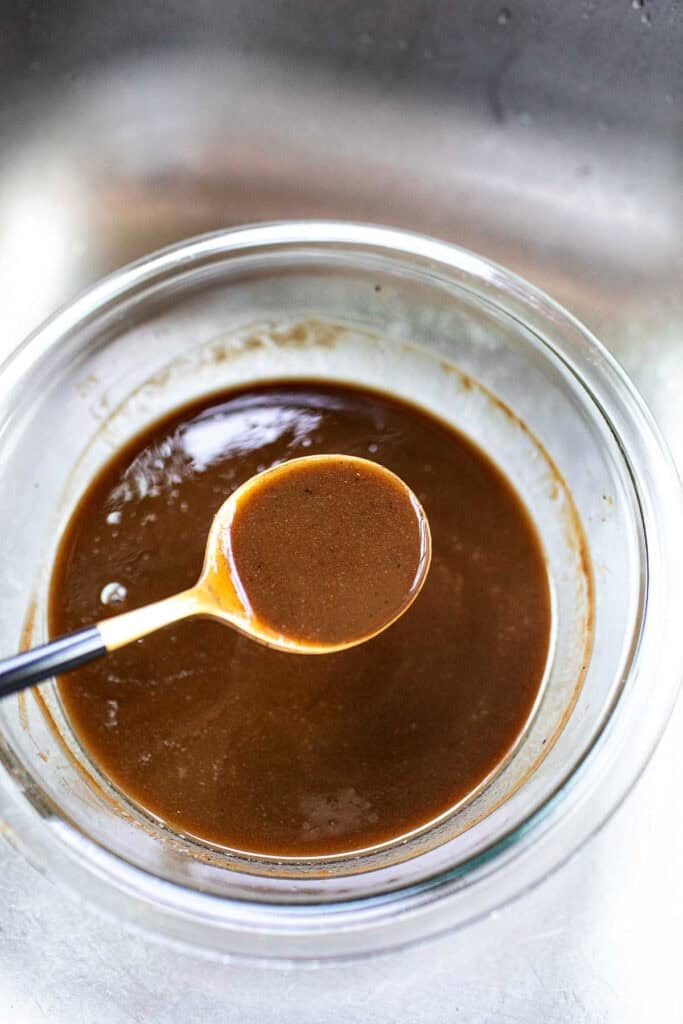 a spoon living Tamarind concentrate from a glass bowl.