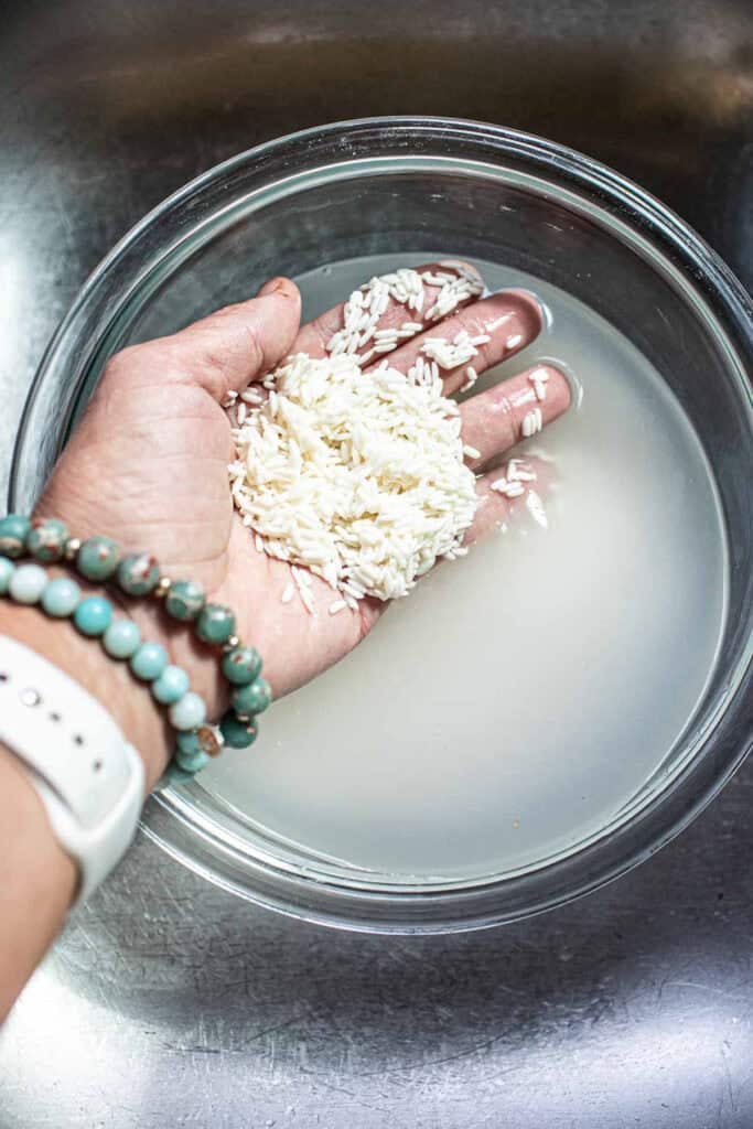 Hand lifing Thai sticky rice from a pan.