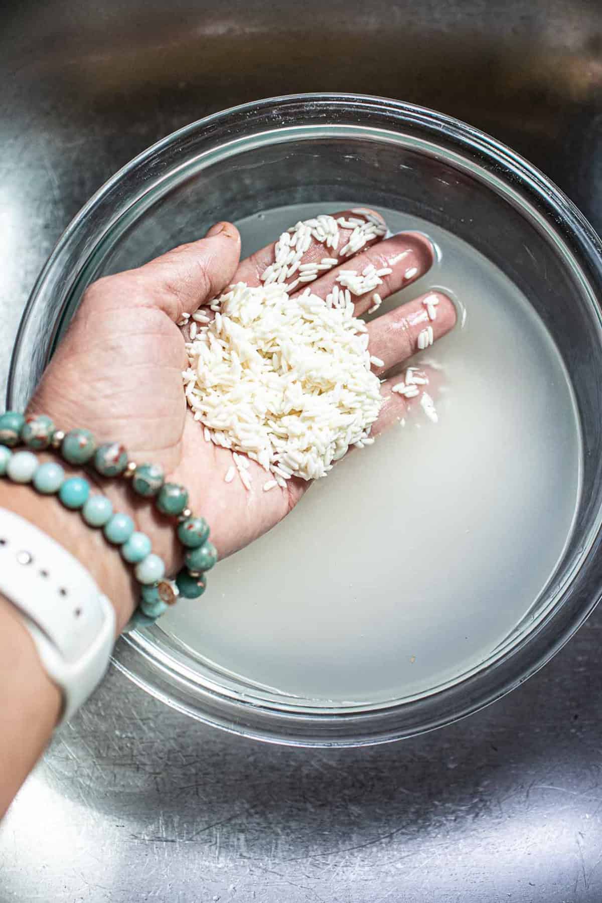 Hand holding sticky rice over water.