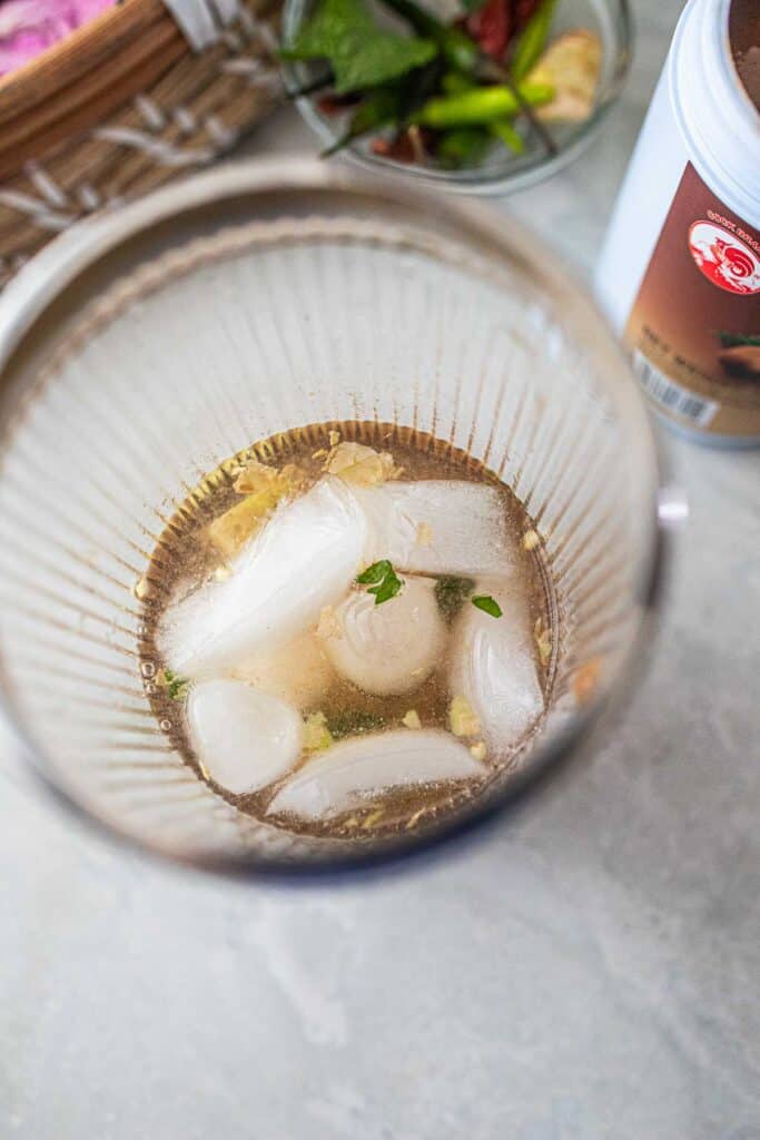 Ice and liquids and herbs in a shaker for Tamarind drink.