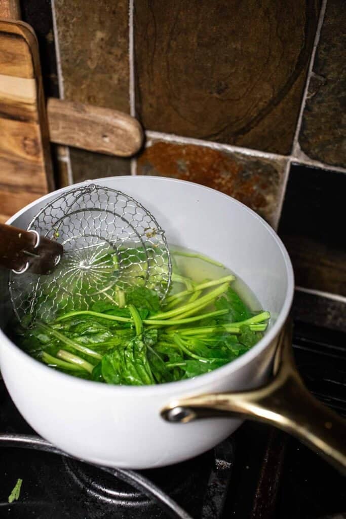 Blanching spinach in a soup pot.